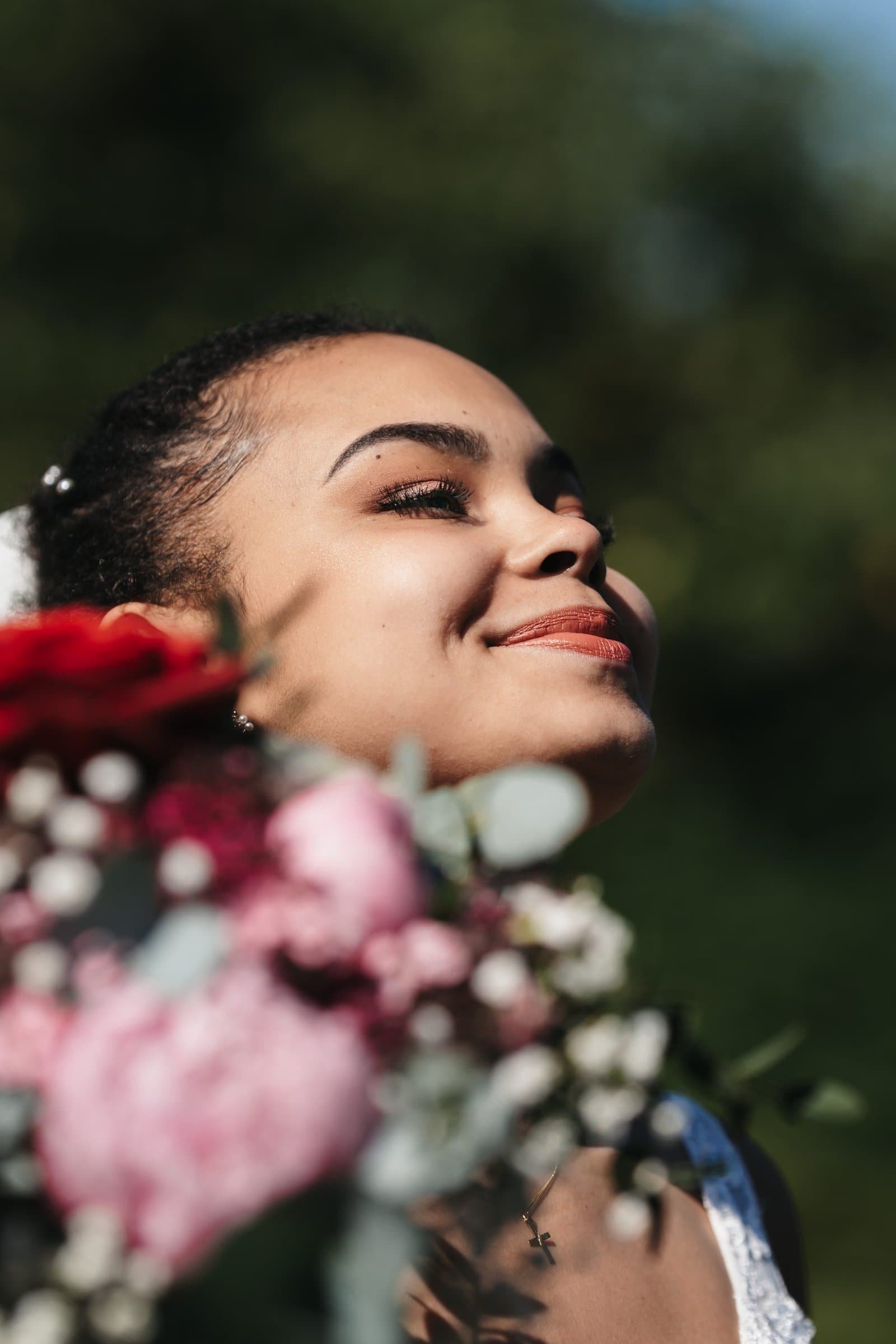 Eine elegante Braut lächelt bei weichem Gegenlicht im Schlossgarten Starnberg, Hochzeitsreportage im Raum München.