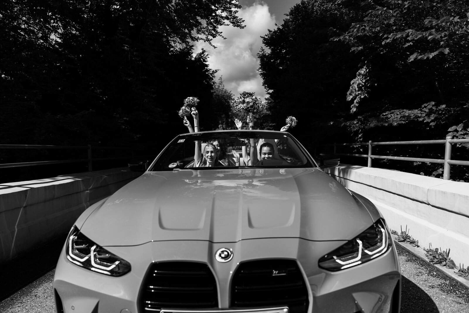 Braut und Trauzeuginnen fahren im offenen BMW Cabriolet vom Starnberger See zur Hochzeitsfeier nach München, Schwarz-Weiß-Reportage.