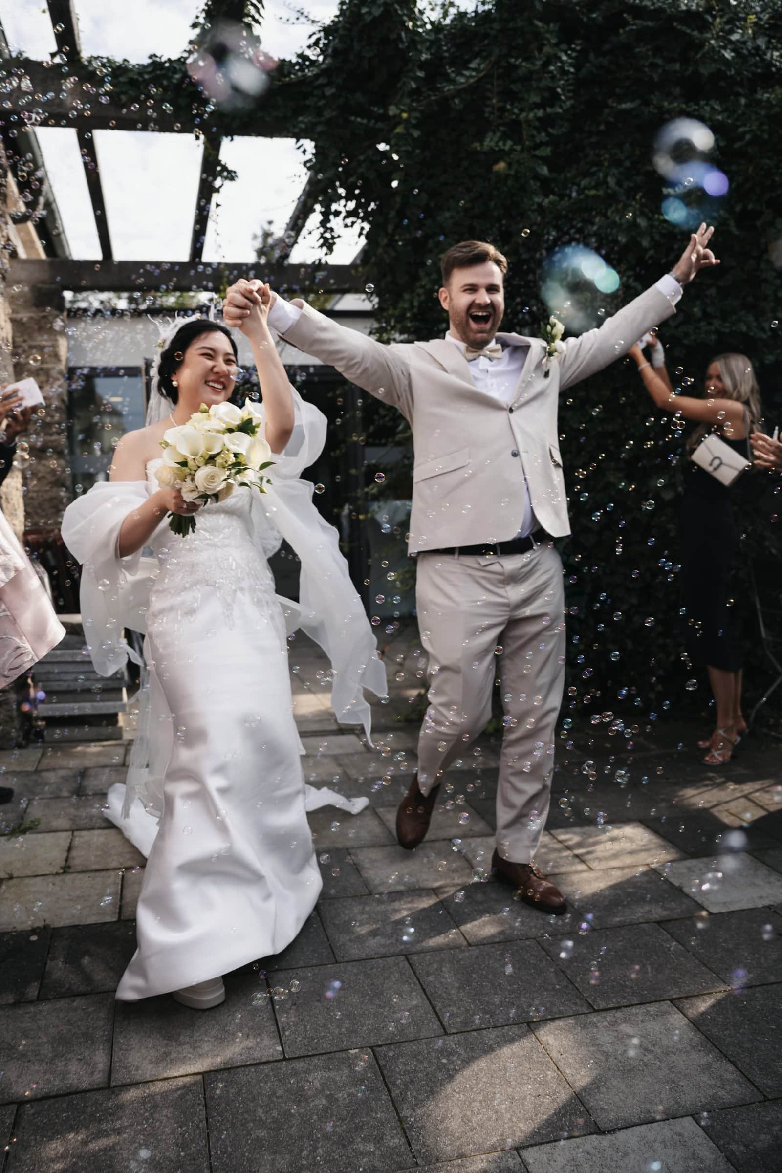 Glückliches Brautpaar beim Jubel mit Seifenblasen, Hochzeitsfotograf München.