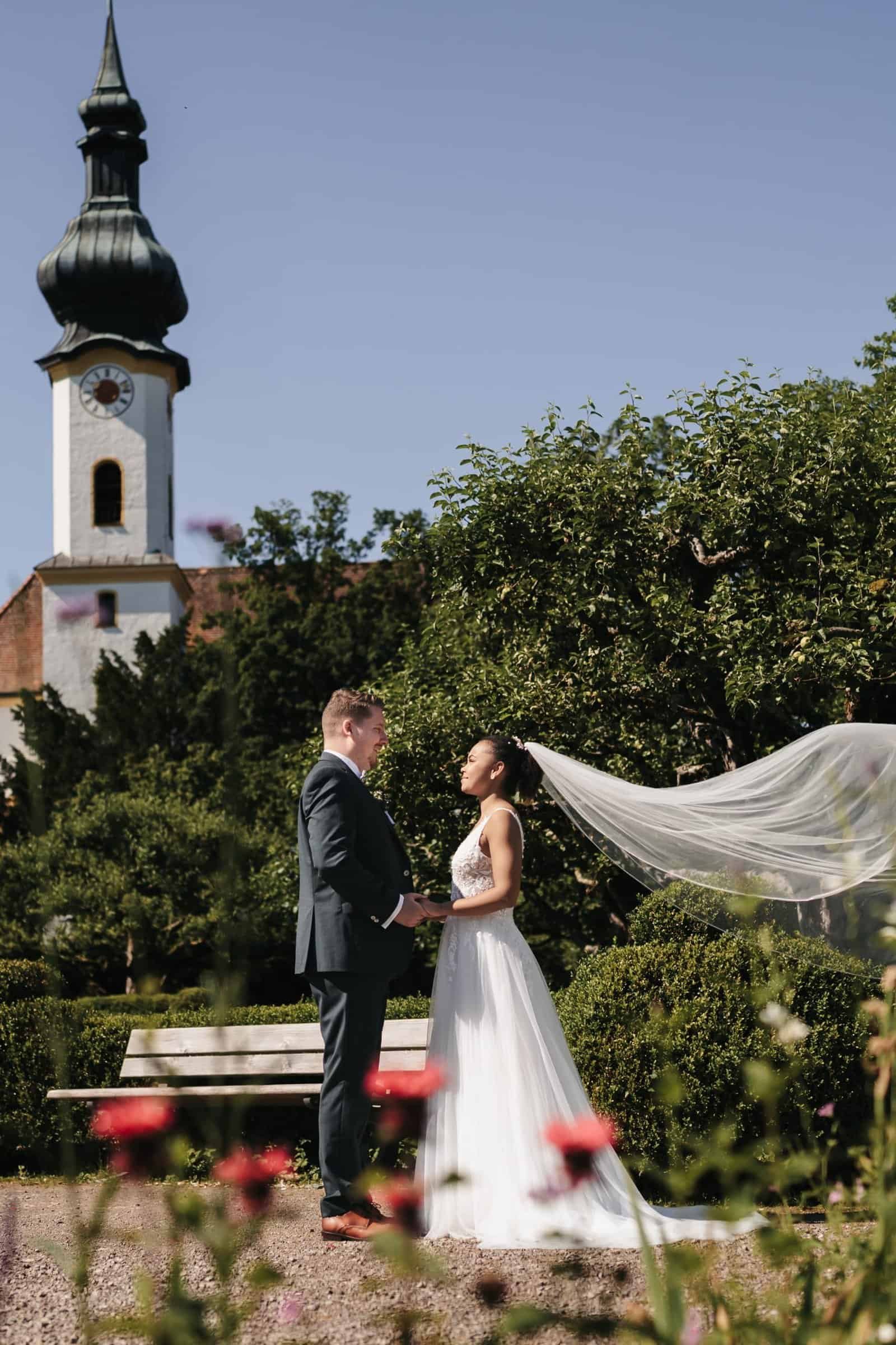 Hochzeitsfotograf in Starnberg: Brautpaar im Schlossgarten Starnberg mit wehendem Schleier, klassische Eleganz für eine Hochzeitsreportage im Raum München.