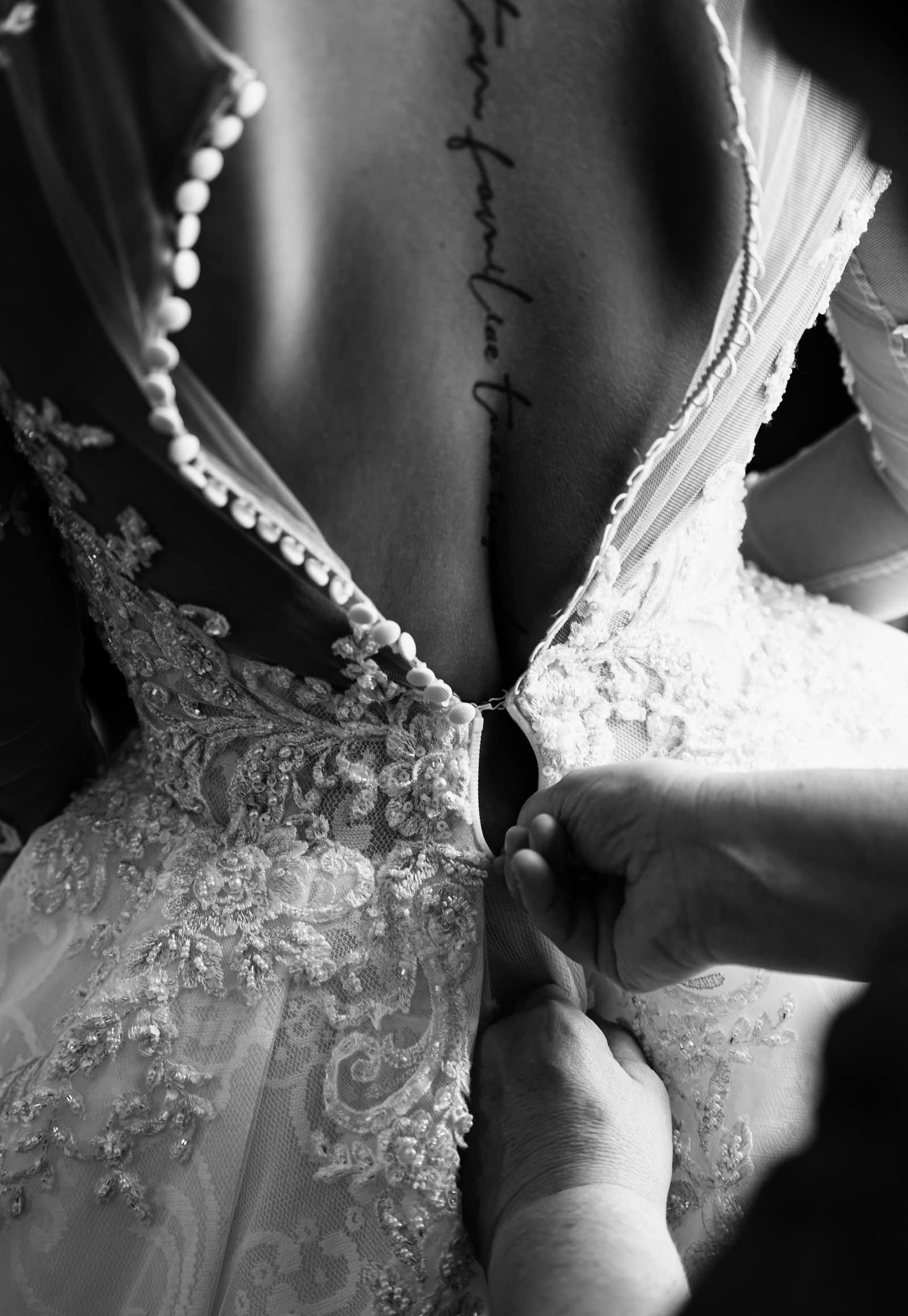 Schließen des Hochzeitskleids durch eine Hand, Nahaufnahme, Hochzeitsfotograf München.