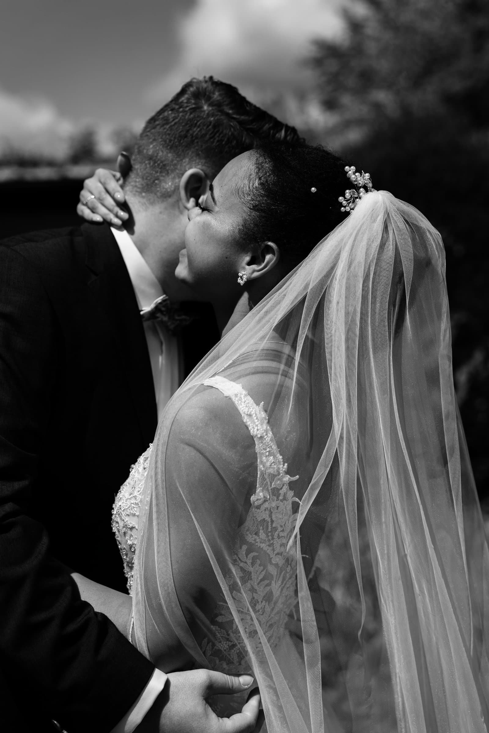 Bräutigam umarmt seine lachende Braut innig während des entspannten Hochzeitsempfangs im Schlossgarten.